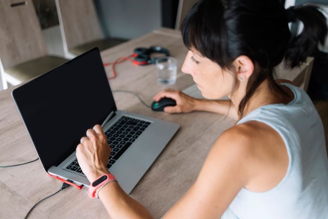 Woman working at desk with blank laptop screen