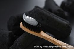 Close up of bamboo toothbrush with charcoal in background for natural oral hygiene bDDX8b