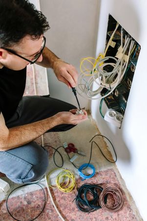 Technician with screwdriver and terminal strip installing telecommunication box