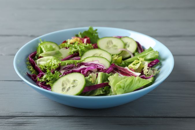 Plate with fresh salad on wooden background, space for text