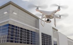 Unmanned Aircraft System Quadcopter Drone UAV In The Air Near Corporate Industrial Building