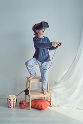 Preteen boy in virtual reality glasses and headphones using joys