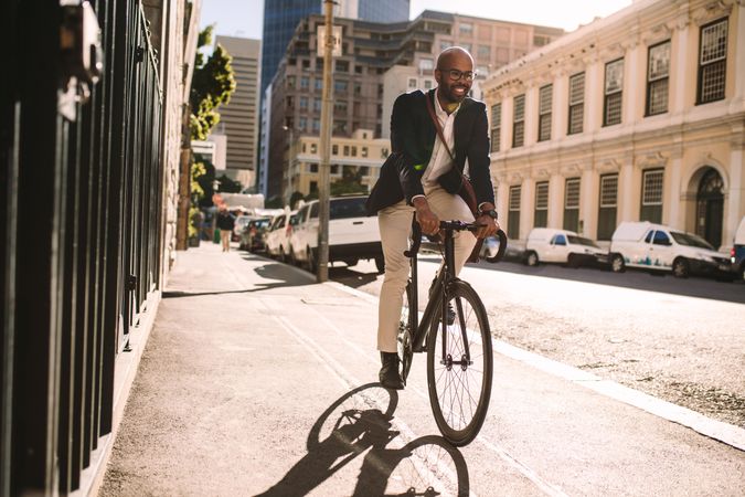 Young smiling businessman going to work by bike
