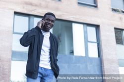 Smiling Black man walking outside talking on his phone 5ng6K2