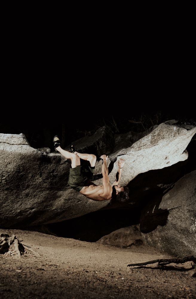 Man practicing rock climbing among large rocks in a forest