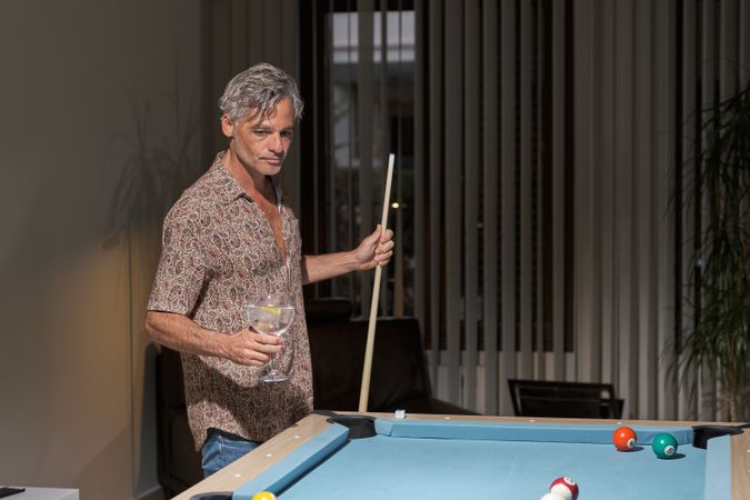 Mature man having drink while playing pool