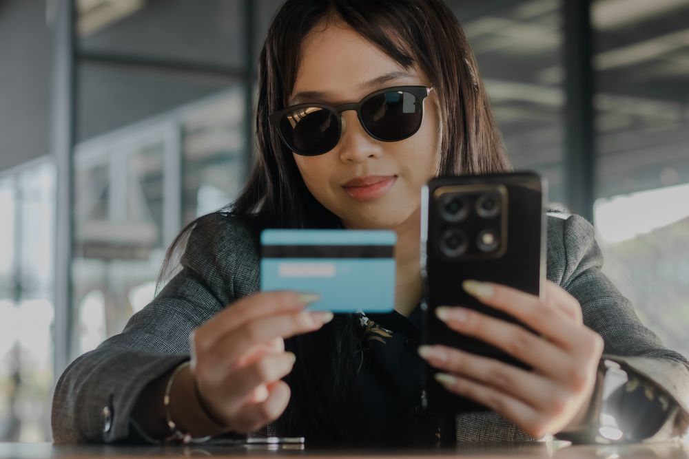 Woman using a smartphone and credit card for online transactions