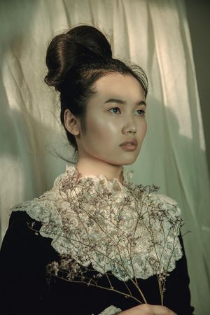 Portrait of young woman in floral collar top holding dried flowers