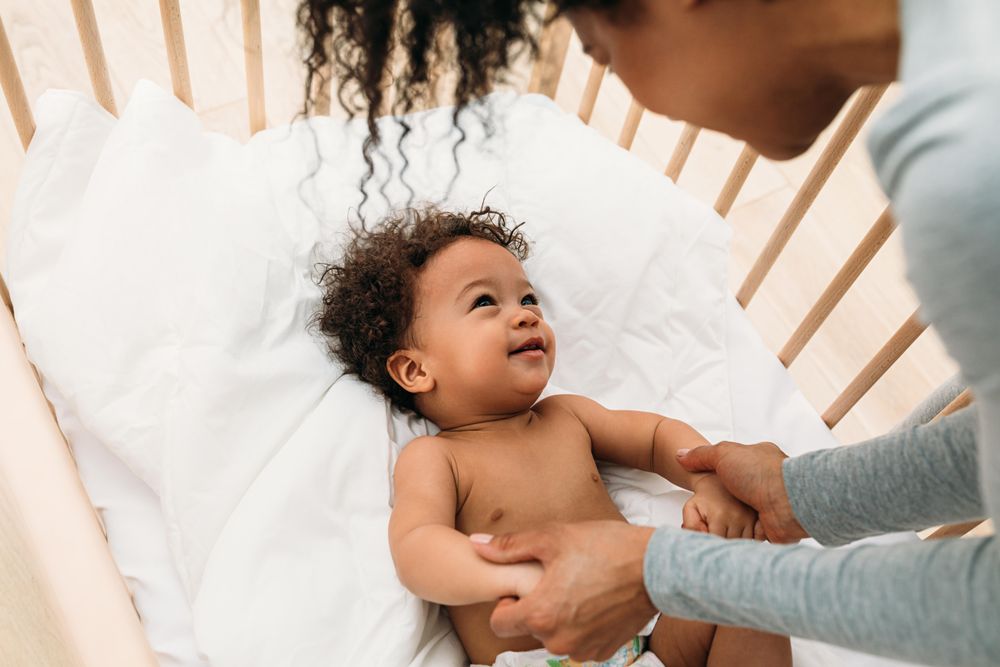 Baby boy in crib smiling up at his mother