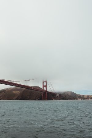 Red bridge construction over wavy dark water