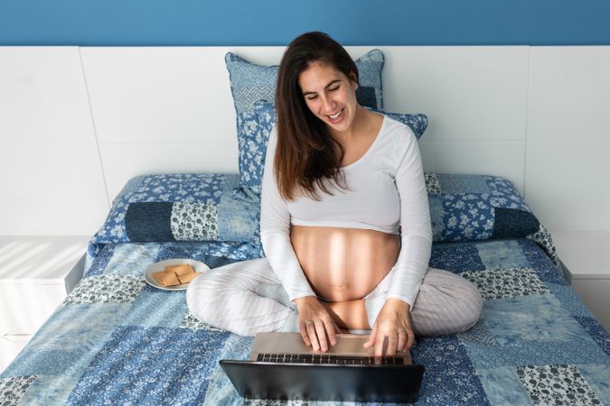 Pregnant woman talking on video chat on laptop