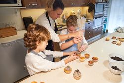 Children helping mother to decorate homemade cupcakes