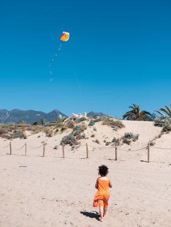 Toddler girl playing with kite on sandy beach