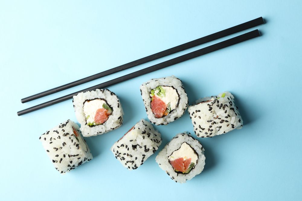 Chopsticks and sushi rolls on blue background. Japanese food
