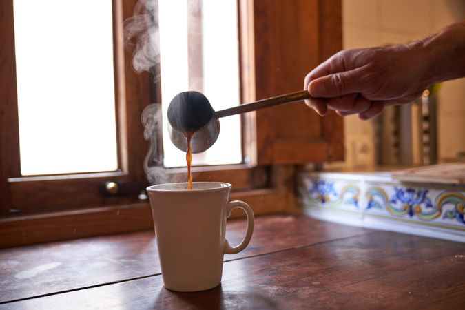 Unrecognizable person pouring coffee into mug
