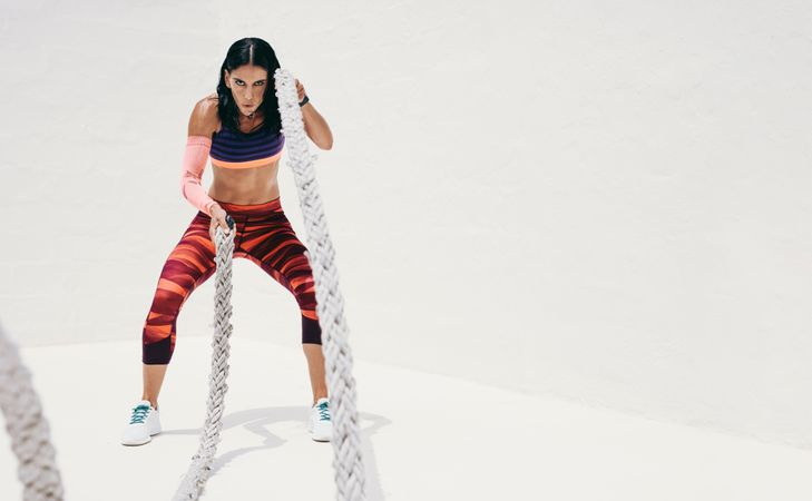 Athletic woman working out with battle ropes
