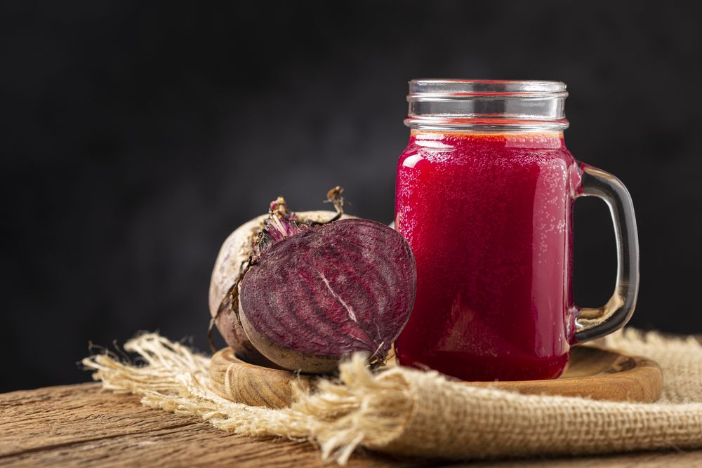 Red beet juice in a glass cup on the wooden table.
