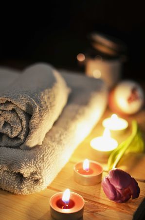 Towels on brown wooden table near lit candles