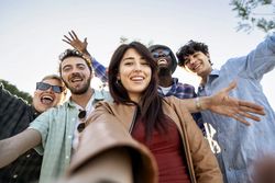 Diverse Gen-Z friends taking joyful selfie on summer day trip