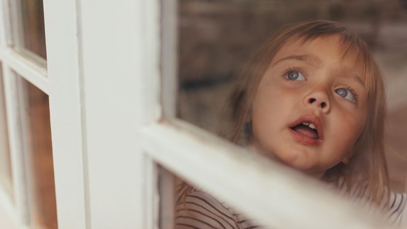 Grey eyed girl looking outside sitting at the window