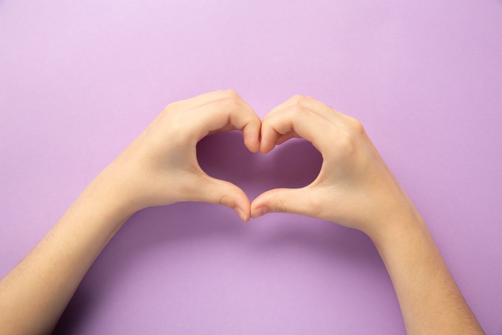 Hands Forming Heart on Purple