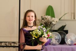 Girl holding bouquet of flowers and smiling at birthday party.