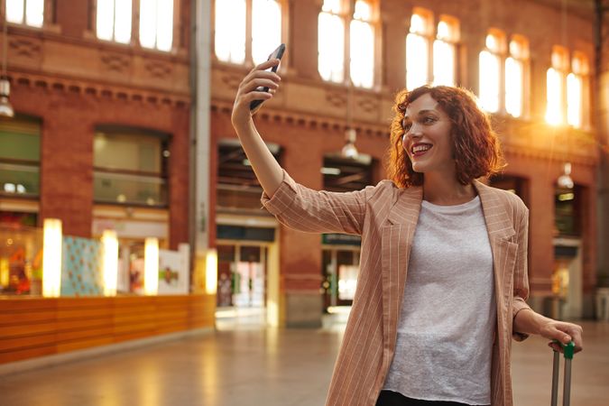 Red haired young woman using smartphone at station