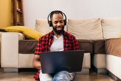 Black man in casual clothes using laptop at home.