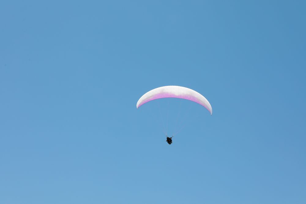 Skydiver with a pink parachute flies across the blue sky