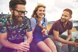 Smiling friends sitting with beer outside