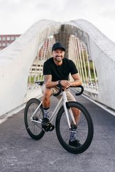 Cheerful man with bicycle standing on footbridge