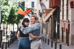 Lesbian couple with LGBT flag walking on street