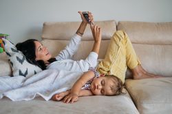 Woman and daughter relaxing on sofa at home