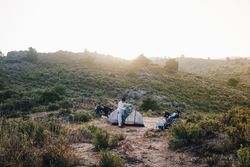 Person setting up a tent in a field, landscape