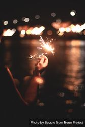 Person holding lighted sparkler at night 5nmqZ0