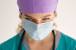 Sad woman in scrubs and mask