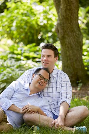 Two men sitting on green grass in the park