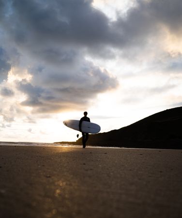 Silhouette of man holding surfboard at the beach
