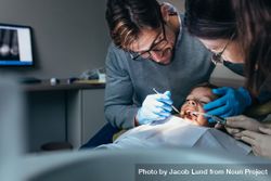 Dentist with female nurse examining a patients teeth at the dental clinic 5rL3Mb