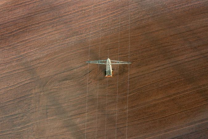 Electricity pylon and agricultural fields, drone view at sunrise