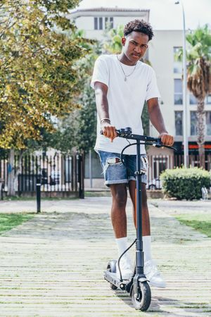 Black man riding on electric scooter in park