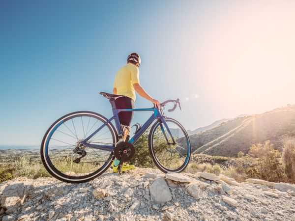 man resting and enjoying the views while riding a bicycle on a mountain road
