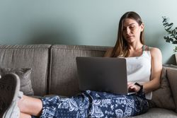 Smiling woman with laptop on couch at home