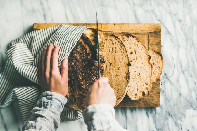 Top view of person slicing bread with knife