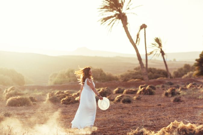 Woman in white dress in dry field in sunlight