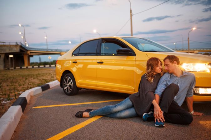 Couple sitting on pavement with yellow card