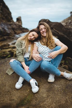 Young sisters sitting on stone on spring day