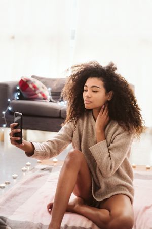 Black woman taking selfie on floor