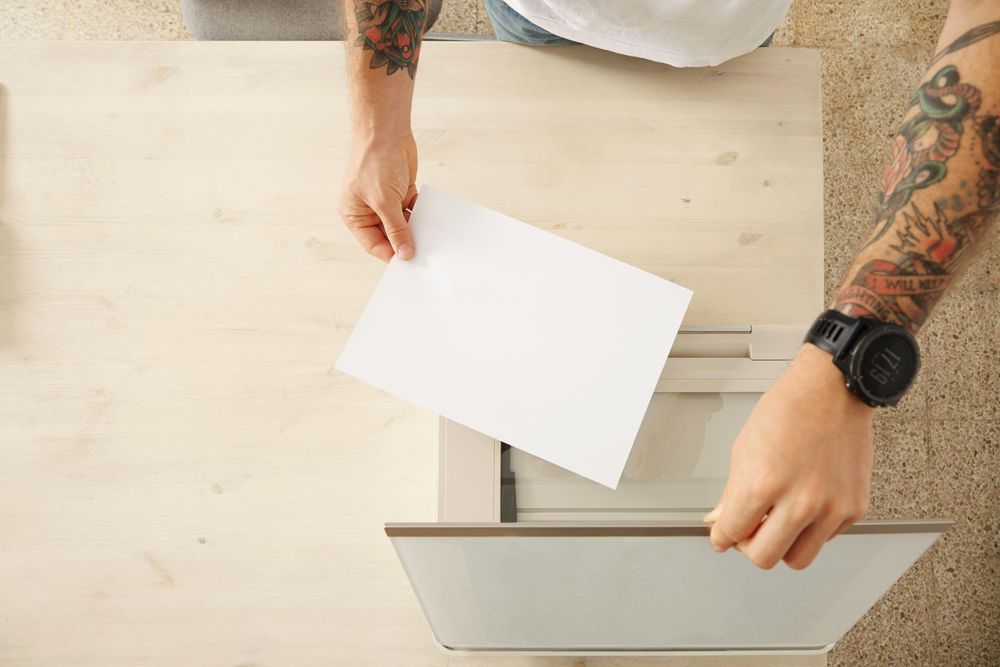 Top view man putting paper in printer