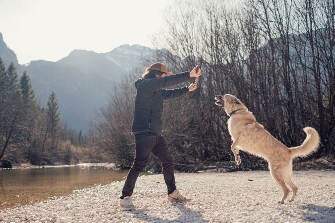 Man playing with dog beside lake
